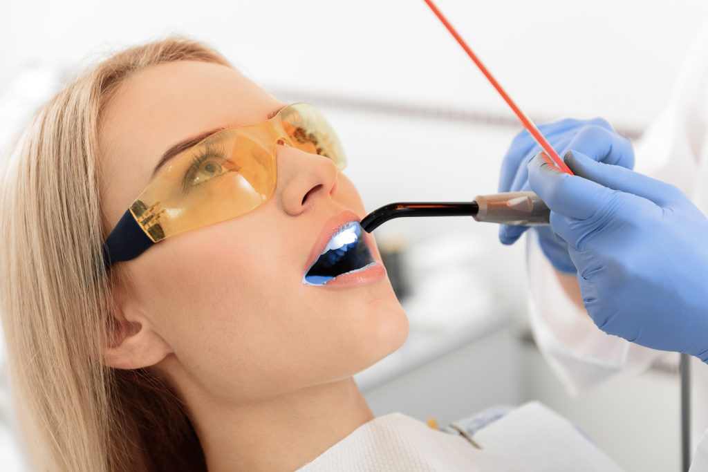 Stomatologist examining mouth of young woman